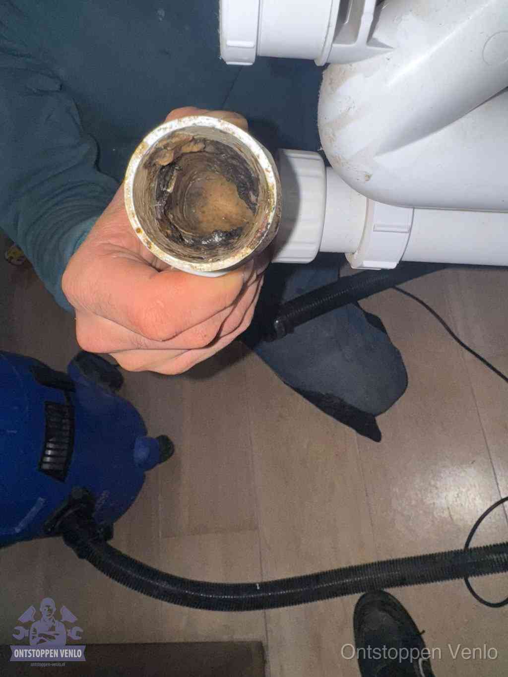 Een losgekoppelde afvoerbuis die van binnen volledig is dichtgeslibd met vet en aanslag, de meest voorkomende oorzaak van een verstopte gootsteen in Venlo