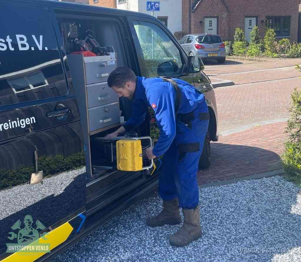 Een monteur pakt buiten op de oprit gereedschap uit de bedrijfsbus, het moment om een professional in te schakelen voor een verstopte afvoer in Venlo