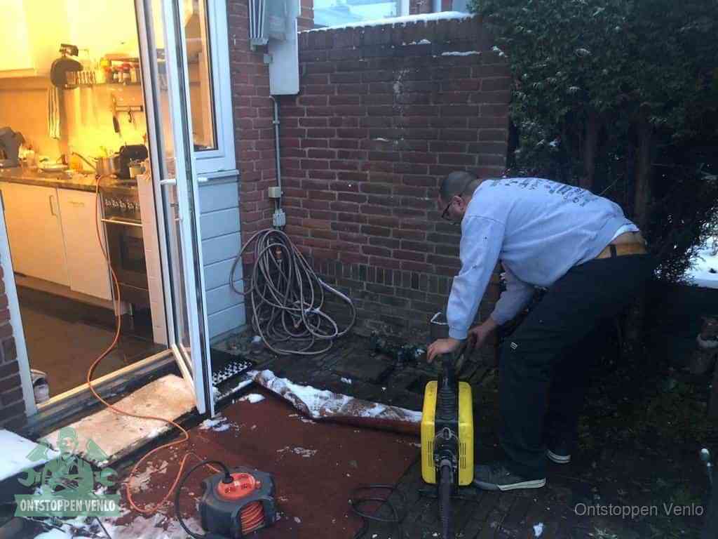 Een monteur werkt buiten bij een open riool-/grondput met een elektrische ontstoppingsmachine om een verborgen afvoerprobleem op te sporen in Venlo