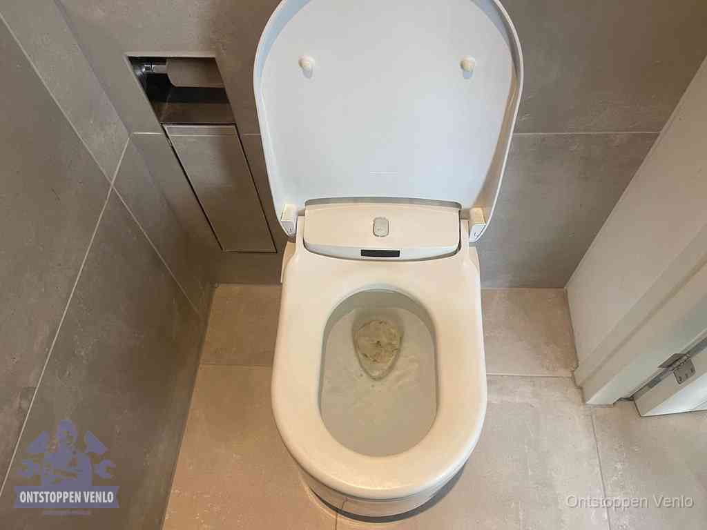 Een wit hangtoilet waarin een prop wc-papier op het water blijft drijven, een duidelijk signaal van een verstopte wc in Venlo