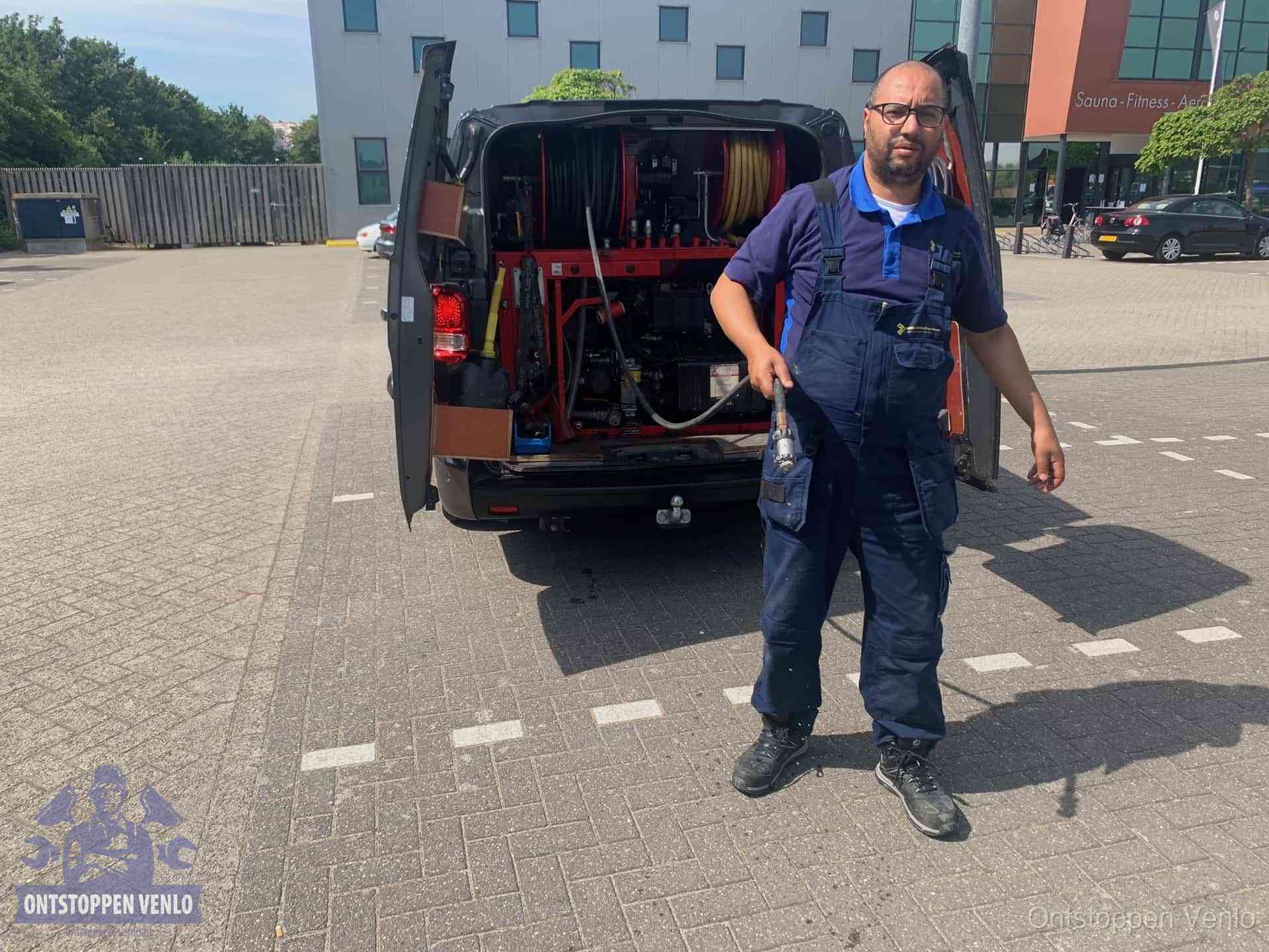 Een monteur bij zijn bestelbus met een hogedruk- en rioolreinigingsunit, klaar om de oorzaak van terugkerende wc-verstoppingen aan te pakken in Venlo