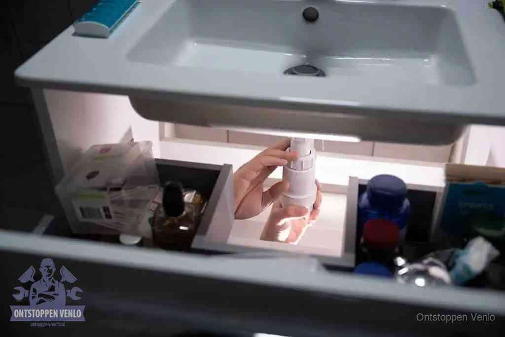 Een pompfles met zeep boven een wastafel in de toiletruimte, de warm water en afwasmiddel-methode om de wc te ontstoppen in Venlo