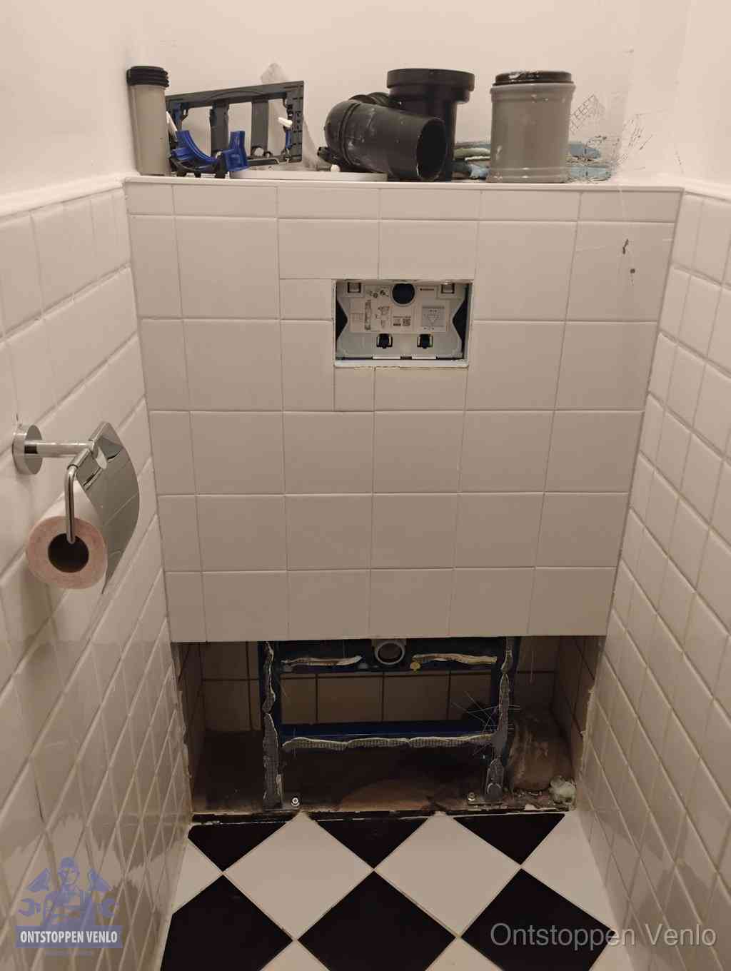 Een toiletruimte waar het hangtoilet en de inbouwreservoir-onderdelen zijn vrijgelegd voor onderhoud, periodiek nazicht voorkomt een wc-verstopping in Venlo