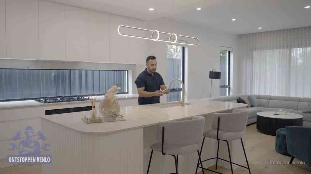Een bewoner bij de keukenspoelbak die zelf aan de slag gaat met een verstopte gootsteen in Venlo
